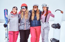 cheerful-women-friends-sports-winter-clothes-with-snowboards-skis-standing-together-hug-looking-camera-snowy-beach_613910-20334
